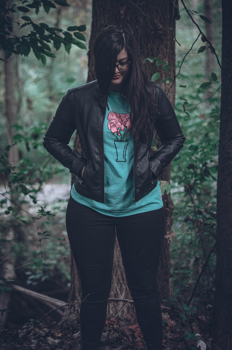 Woman stands in trees wearing the green bouquet of audio cables tee 