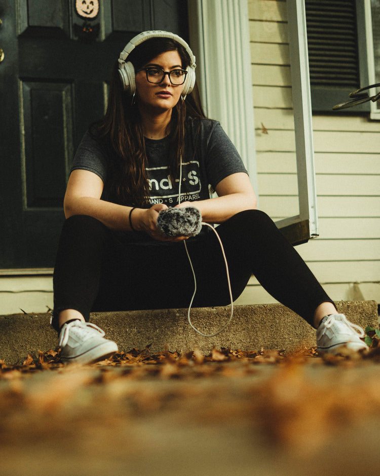 Woman sits on stoop wearing navy Command S Apparel logo tee